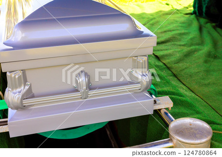 Silver coffin is placed on green cloth, ready for burial service during burial ceremony. 124780864