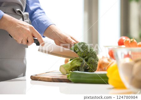 Hands of a middle-aged woman cutting vegetables 124780984