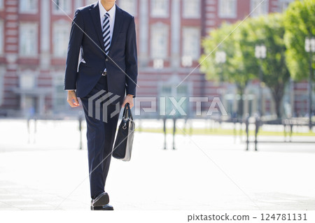 一位穿著西裝的年輕男子的腳走過商業區 124781131