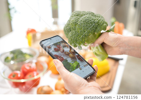 一位中年婦女的手用智慧型手機拍攝烹飪食材 124781156