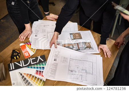 Architectural team reviewing construction blueprints, discussing project details at desk, collaboration in architecture concept 124781236
