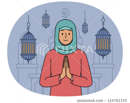 Muslim woman in hijab makes prayer gesture standing near mosque and traditional islamic lanterns 124781335