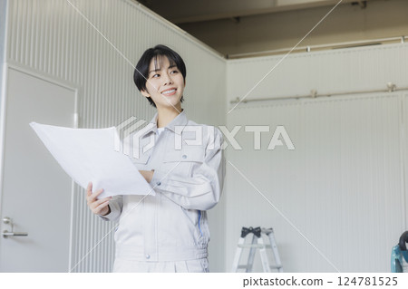A woman in work clothes looking at a drawing in a factory 124781525