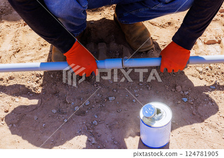 Contractor in gloves connects two electrical plastic pipes on construction site with during foundation work 124781905
