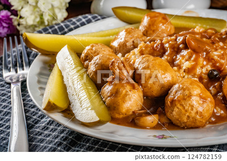 Chicken meatballs and mushrooms gravy served with groats bulgur and pickled cucumber. Chicken meatballs and mushrooms gravy served with groats bulgur and pickled cucumber. 124782159