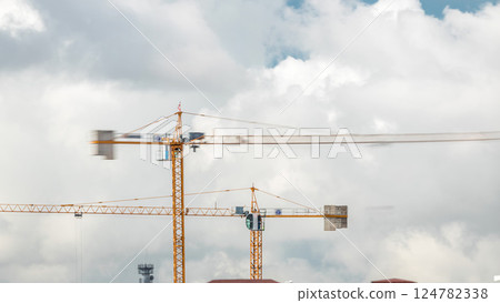 Big construction site including several cranes working and moving on a building complex, with cloudy sky timelapse 124782338