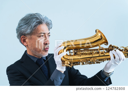 A middle-aged man inspecting a saxophone. Appraiser, repairman, and instrument craftsman 124782808