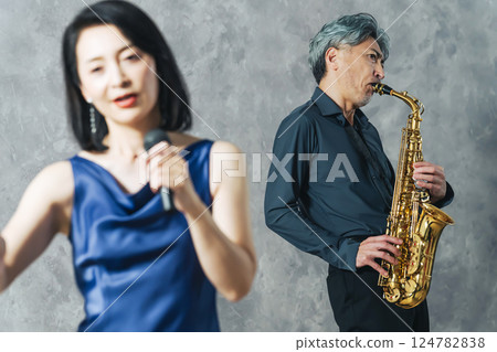一名男子吹奏薩克斯風,女歌手唱歌 一名男子吹奏薩克斯風,女歌手唱歌 124782838