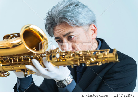 一名中年男子正在檢查薩克斯風。鑑定師、修理工、儀器工匠 一名中年男子正在檢查薩克斯風。鑑定師、修理工、儀器工匠 124782873