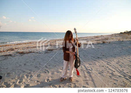 Girl Plays Bass Music Instrument On The Beach At Sunset Near Ocean Girl Plays Bass Music Instrument On The Beach At Sunset Near Ocean 124783076