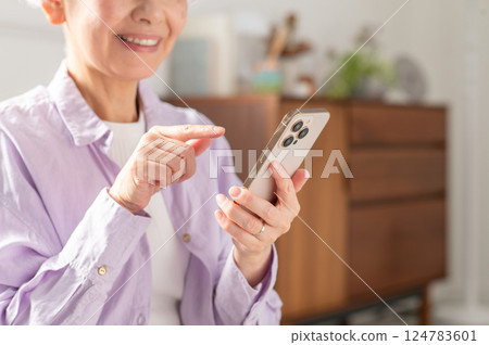 Senior woman operating a smartphone (parts) 124783601