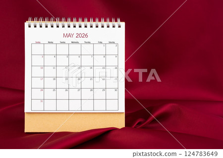 Front view of May 2026 desk calendar on red silk background. 124783649