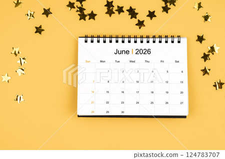 June 2026 calendar and scattered sparkling yellow confetti stars on a yellow. 124783707