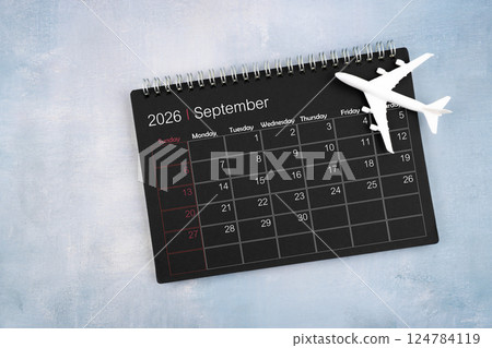 September 2026 black calendar and airplane toy on wooden table. 124784119