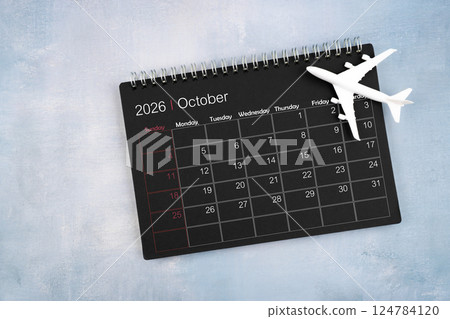 October 2026 black calendar and airplane toy on wooden table. October 2026 black calendar and airplane toy on wooden table. 124784120