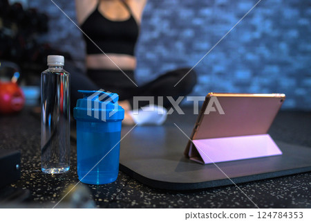 Tablet: Cool woman exercising at the gym while watching YouTube videos, stretching, watching videos Tablet: Cool woman exercising at the gym while watching YouTube videos, stretching, watching videos 124784353