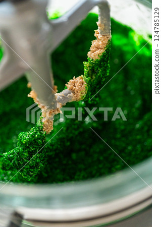 The vibrant green dough mixture for Vibrant Green Gingerbread Cookies for Festive Baking is starting to form, combining butter, sugar, and the green-tinted maple syrup in a mixer. 124785129