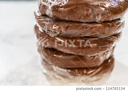 Multiple wrapped dough disks stacked, ready for refrigeration, setting up for batch baking later. 124785134