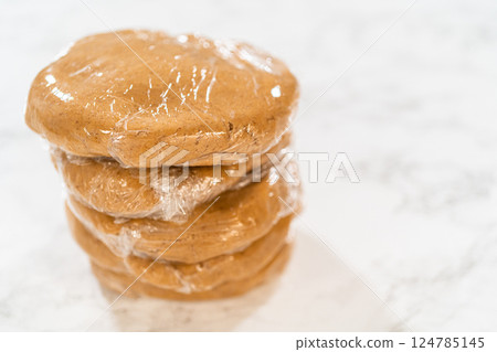 Stacked view of multiple discs of Amber Gingerbread Cookie Dough, each individually wrapped in plastic wrap, ready to be stored or chilled. The layers are neatly stacked, showing careful preparation Stacked view of multiple discs of Amber Gingerbread Cookie Dough, each individually wrapped in plastic wrap, ready to be stored or chilled. The layers are neatly stacked, showing careful preparation 124785145