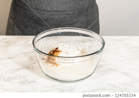 Eye-level view of a mixing bowl containing dry ingredients for Classic Gingerbread Cookie Dough, including flour, baking powder, and spices like cinnamon, ginger, and cloves. These ingredients are 124785154