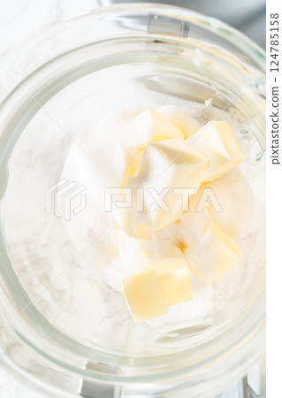Top view of sugar and butter cubes in a mixing bowl, ready to be creamed together as the first step in making Classic Sugar Cookie Dough. The ingredients are positioned for blending, a key step for Top view of sugar and butter cubes in a mixing bowl, ready to be creamed together as the first step in making Classic Sugar Cookie Dough. The ingredients are positioned for blending, a key step for 124785158