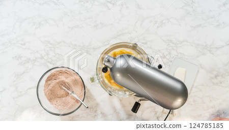 Overhead setup with an electric mixer and bowls of prepared dry and wet ingredients for Pale Gingerbread Cookies with Subtle Spice Flavor. A whisk rests in the flour mixture, ready to combine Overhead setup with an electric mixer and bowls of prepared dry and wet ingredients for Pale Gingerbread Cookies with Subtle Spice Flavor. A whisk rests in the flour mixture, ready to combine 124785185