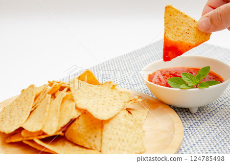 Tortilla chips and salsa sauce - Holding chips in hand and dipping them in salsa sauce Tortilla chips and salsa sauce - Holding chips in hand and dipping them in salsa sauce 124785498