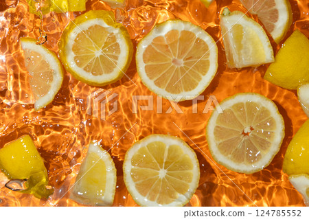 Slices of fresh lemons in water, splash of water, fresh orange background, top view 124785552
