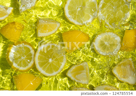 Vibrant yellow lemon pieces floating in motion water Vibrant yellow lemon pieces floating in motion water 124785554