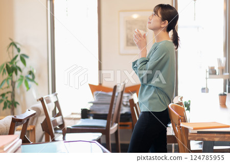 女人站著放鬆,一邊喝咖啡 女人站著放鬆,一邊喝咖啡 124785955