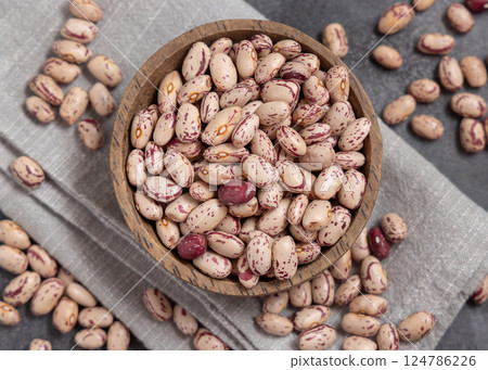 Wooden bowl full of dried pinto beans on napkin on gray top view. Traditional Latin American legumes Wooden bowl full of dried pinto beans on napkin on gray top view. Traditional Latin American legumes 124786226