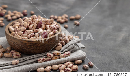 Wooden bowl full of dried pinto beans on napkin on gray closeup. Traditional Latin American legumes Wooden bowl full of dried pinto beans on napkin on gray closeup. Traditional Latin American legumes 124786227