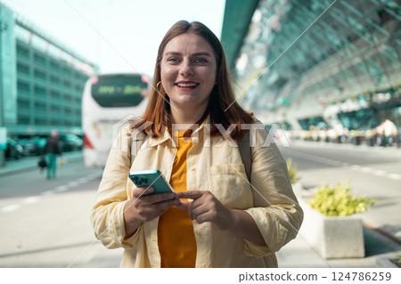 Smiling woman holding smartphone at the airport Smiling woman holding smartphone at the airport 124786259