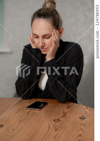 a woman experiencing headache migraine while sitting on a couch in Young modern living room home during daytime vertical photo 124786955