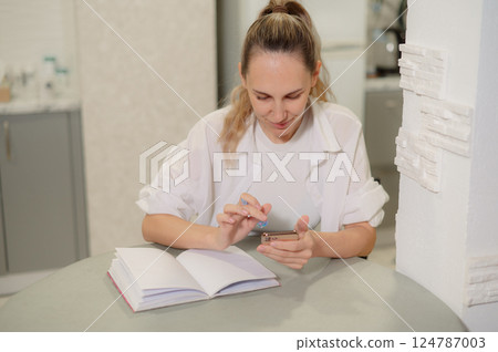 Close up of at a hands checking smart phone calendar and writing on agenda t woman home 124787003