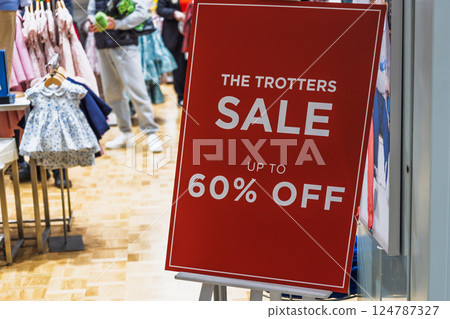 Red sale sign in clothing store offering up to 60 percent off during promotion 124787327