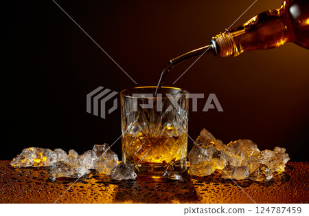 Whiskey pours from bottle to glass. Whiskey pours from bottle to glass. 124787459