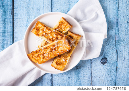 Close up of appetizing croutons in powdered sugar on a plate on the table top view Close up of appetizing croutons in powdered sugar on a plate on the table top view 124787658