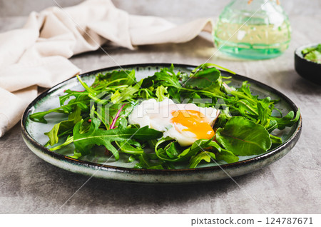 Poached egg in arugula and chard leaves on a plate on a table 124787671
