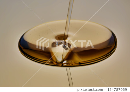 Texture of pouring cosmetic oil on a golden background. Texture of pouring cosmetic oil on a golden background. 124787969