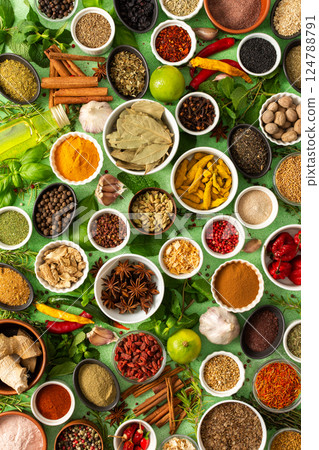 Fresh, fragrant spices and herbs arranged in an array of colors, sitting on a soft green backdrop, bringing flavor and zest to any kitchen 124788791