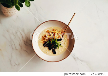 A bowl of oatmeal cooked in chicken broth, topped with fried mushrooms and green onions, arranged in a clean, minimalistic aesthetic A bowl of oatmeal cooked in chicken broth, topped with fried mushrooms and green onions, arranged in a clean, minimalistic aesthetic 124788959