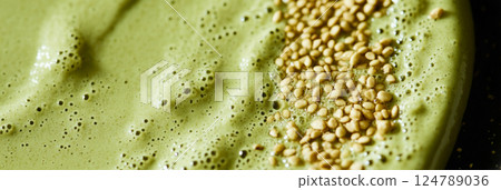 A matcha smoothie bowl, garnished with nuts and sesame seeds, sits in soft, natural light. Shadows stretch from the side of the window, adding depth and contrast to the healthy breakfast scene, banner 124789036