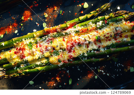 Fresh asparagus grilled to perfection, sprinkled with chili flakes and Parmesan cheese, served on a plate. A crunchy, healthy, and flavorful side dish, ideal for any meal or light lunch 124789069