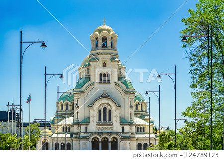 Frontal view of Alexander Nevsky Cathedral in Sofia, Bulgaria, bright sunlight, symmetrical green domes and grand religious design. Cathedral stands as symbol of history, faith, cultural pride 124789123