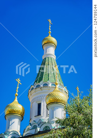 Golden onion domes of St. Nicholas the Miracle-Maker, under vivid blue sky in Sofia, Bulgaria. Church domes reflect faith, tradition and spiritual heritage Golden onion domes of St. Nicholas the Miracle-Maker, under vivid blue sky in Sofia, Bulgaria. Church domes reflect faith, tradition and spiritual heritage 124789144