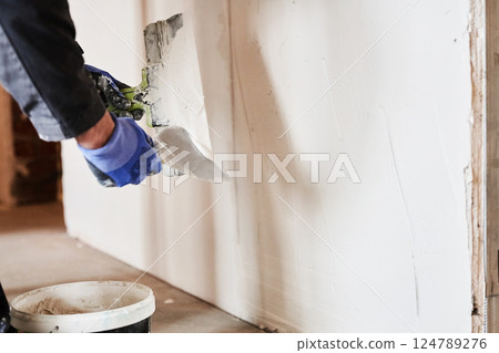 The worker's hands putty the wall with a spatula. Apartment renovation. Sealing openings between drywall. With space to copy. High quality photo The worker's hands putty the wall with a spatula. Apartment renovation. Sealing openings between drywall. With space to copy. High quality photo 124789276