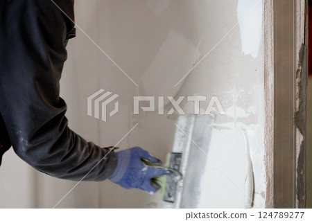 The worker's hands putty the wall with a spatula. Apartment renovation. Sealing openings between drywall. With space to copy. High quality photo The worker's hands putty the wall with a spatula. Apartment renovation. Sealing openings between drywall. With space to copy. High quality photo 124789277