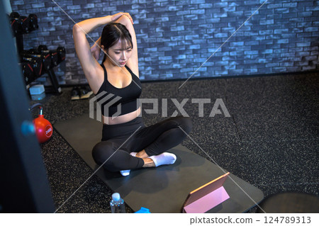 A cool woman exercising at the gym while watching YouTube videos on a tablet Stretching How to do it Video viewing 124789313