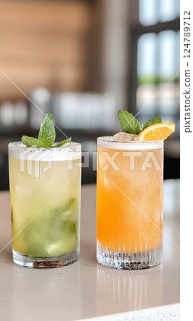 Two vibrant cocktails topped with fresh mint and citrus slices are elegantly displayed on a marble bar in a modern venue filled with ambiance 124789712